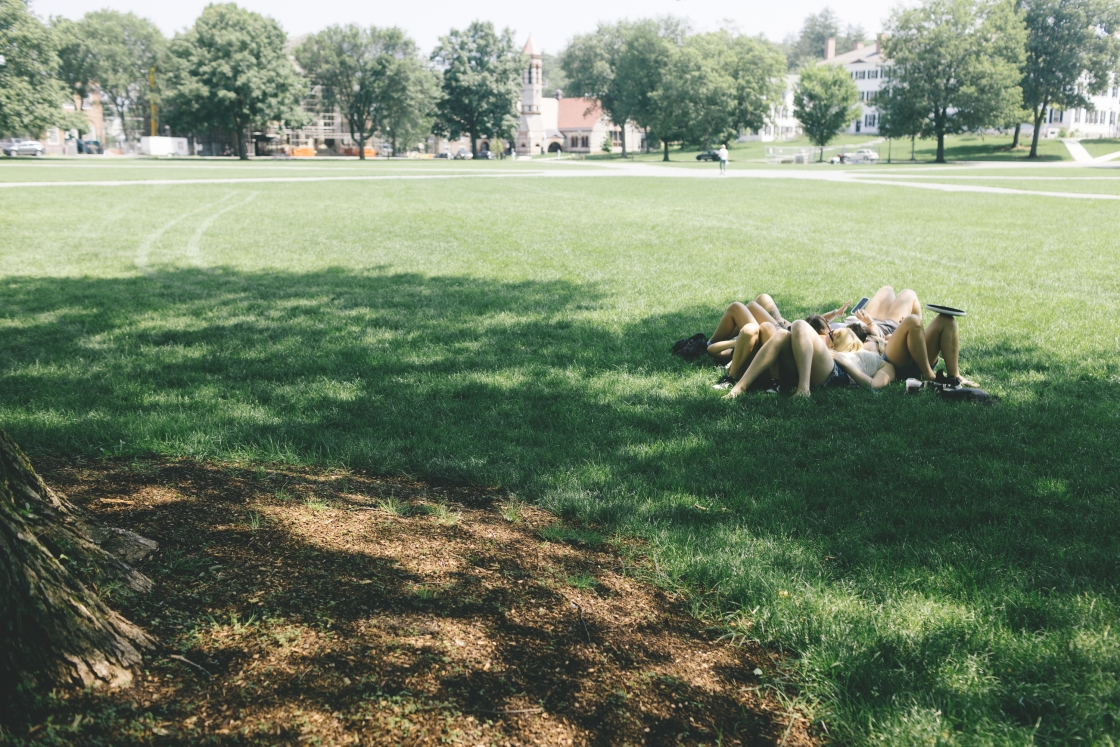 A cluster of friends lie under a tree on the Green