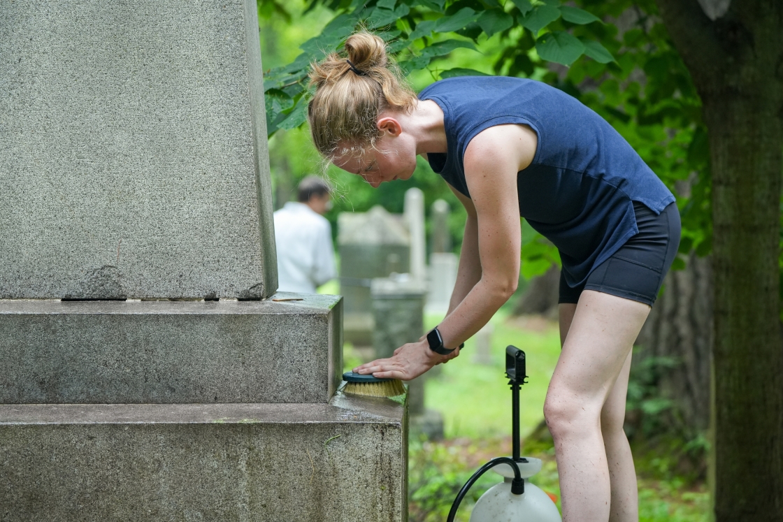Carolyn Roche, a research assistant in the Department of Microbiology and Immunology, cleans one of the headstone in the Dartmouth cemetery.