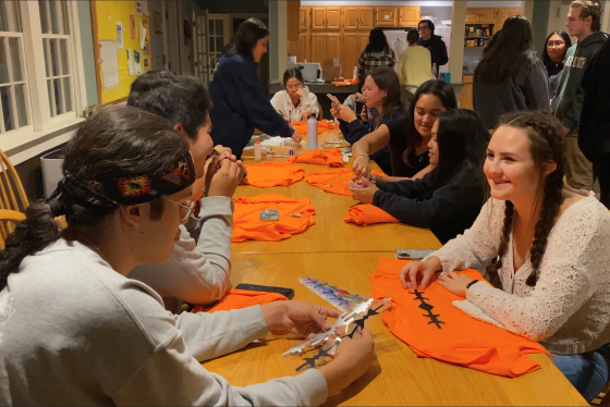 Students decorating orange shirts around a table