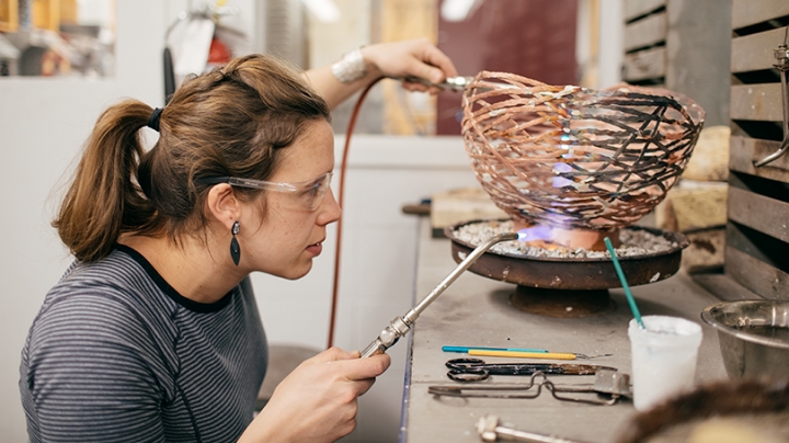an artist welding a copper bowl together