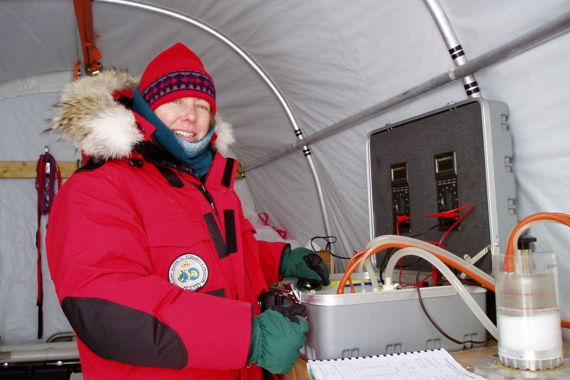 person in red parka next to science equipment