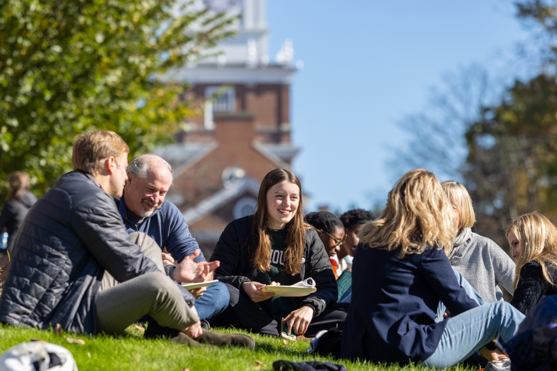 Students and families enjoy a picnic on the green grass at Dartmouth