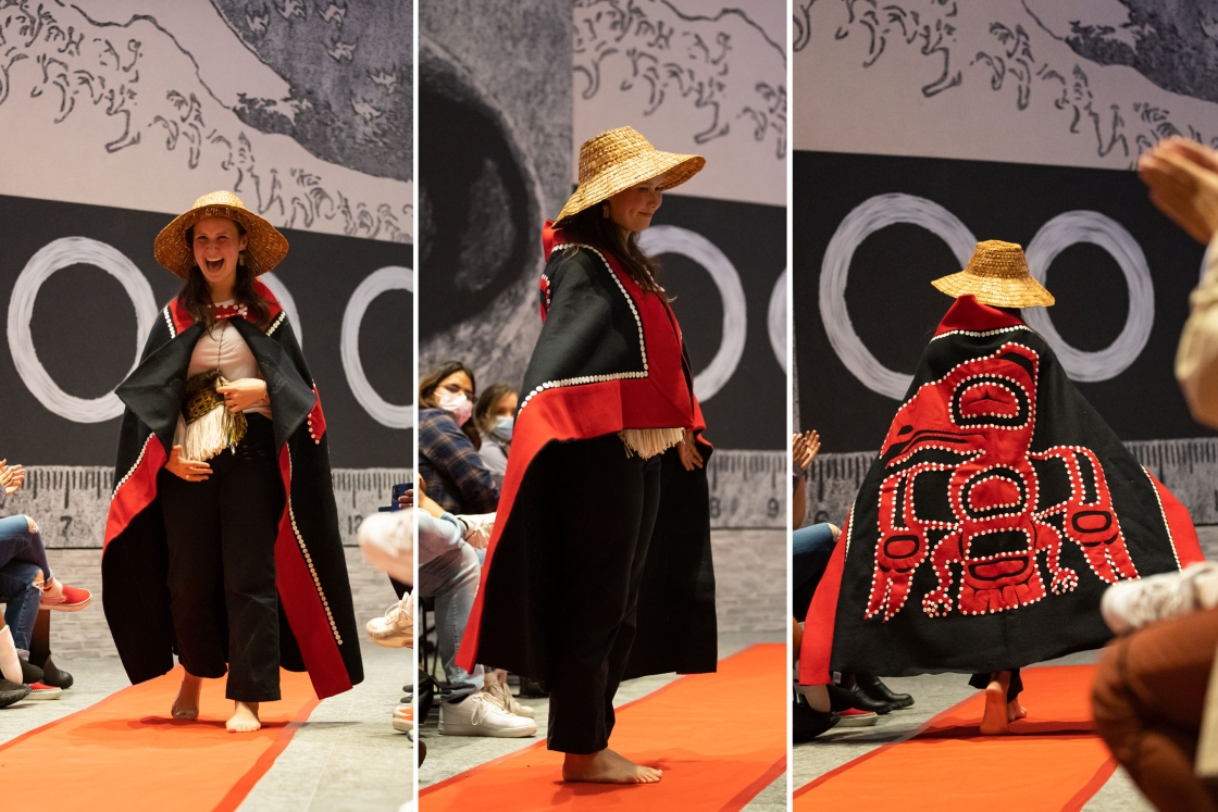 Model walks the &quot;runway&quot; in the Hood Museum wear a red &amp; black cape and a wide-brimmed straw hat.