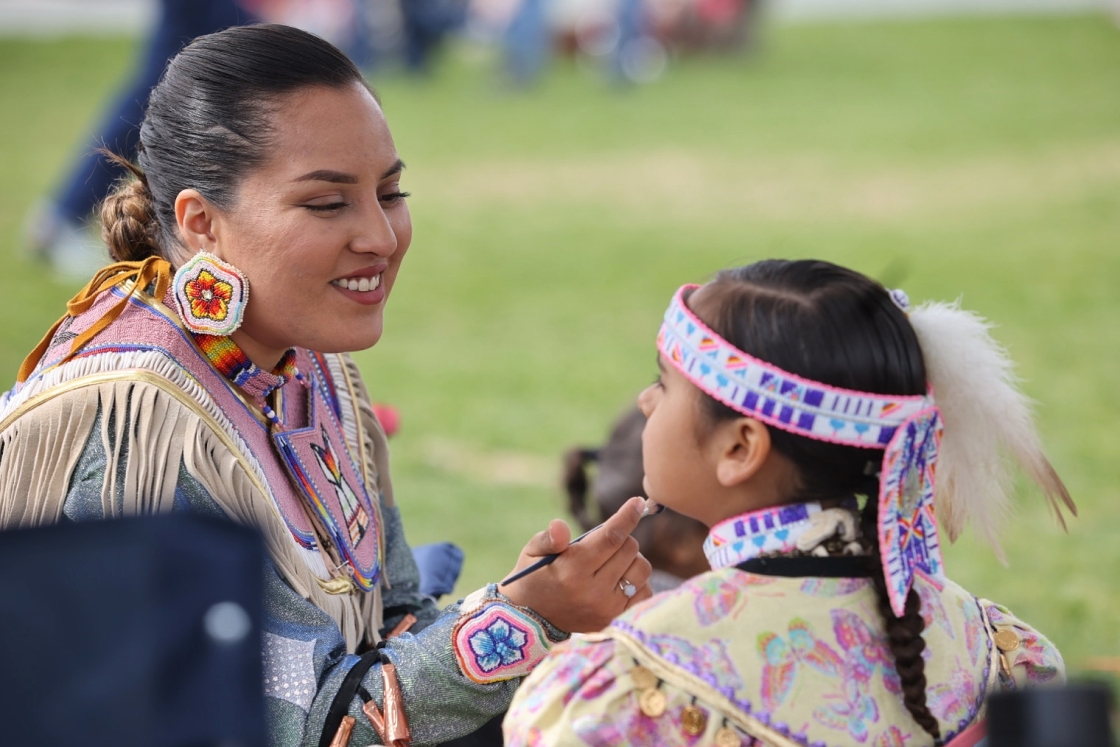 A woman painting a child's face at the Powwow