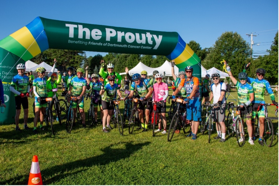 A group of cyclists standing under an inflatable sign for The Prouty.