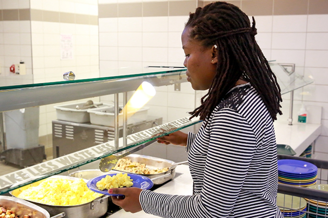 a student filling her plate with scrambled eggs in 53 Commons dining hall