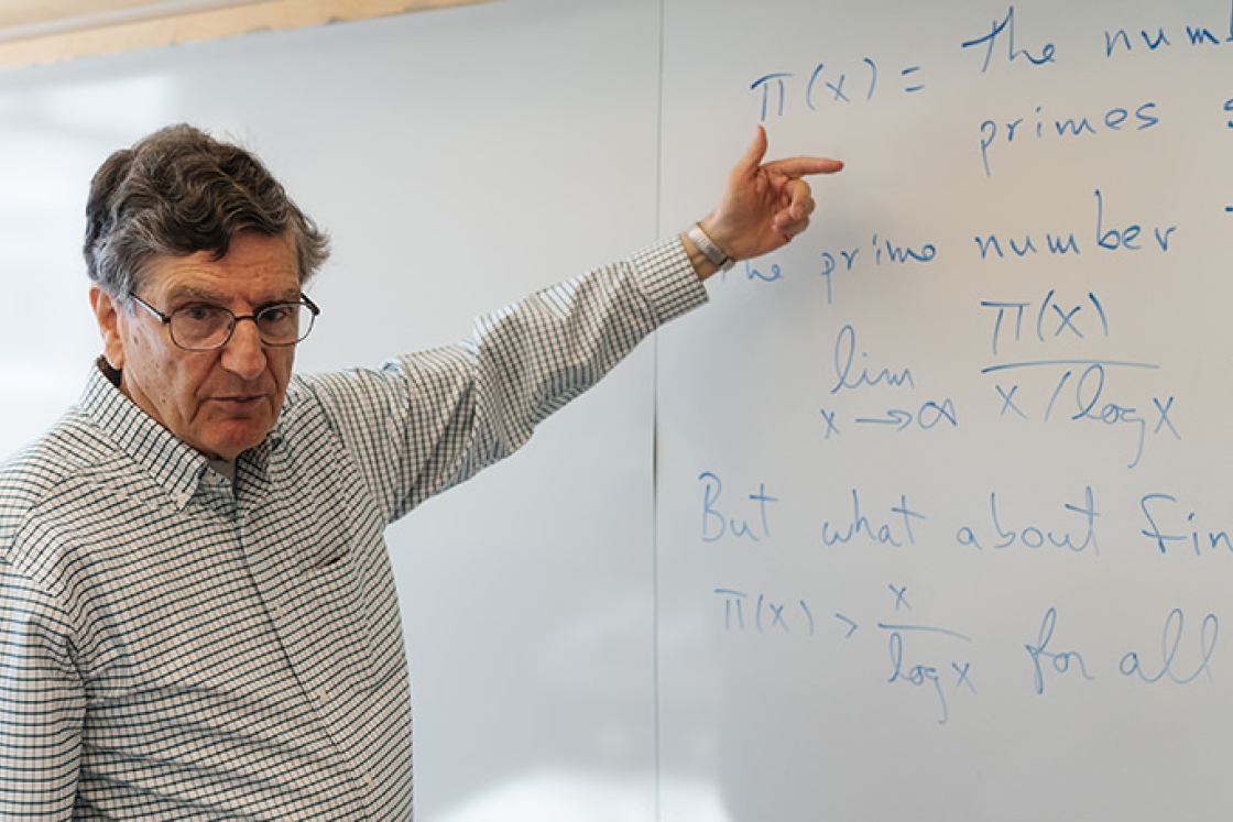 Mathematics professor emeritus Carl Pomerance points to a whiteboard
