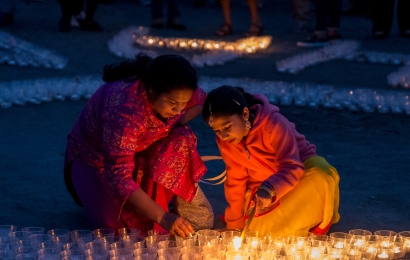Two women in saris lighting the candles during a celebration of Diwali.