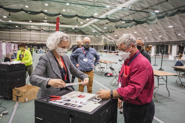 Hanover Town Clerk Betsy McClain collects tally tapes from a voting machine in Leverone Field House.