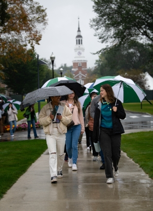 Families walk down Tuck Mall with umbrellas